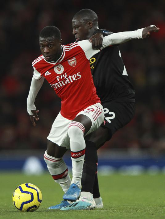 Penyerang Arsenal,  Nicolas Pepe (depan) mengontrol bola dari kawalan pemain Manchester City, Benjamin Mendy  pada pertandingan lanjutan Liga Inggris di di Stadion Emirates, London (15/12/2019). City menang telak atas Arsenal 3-0. (AP Photo/Ian Walton)
