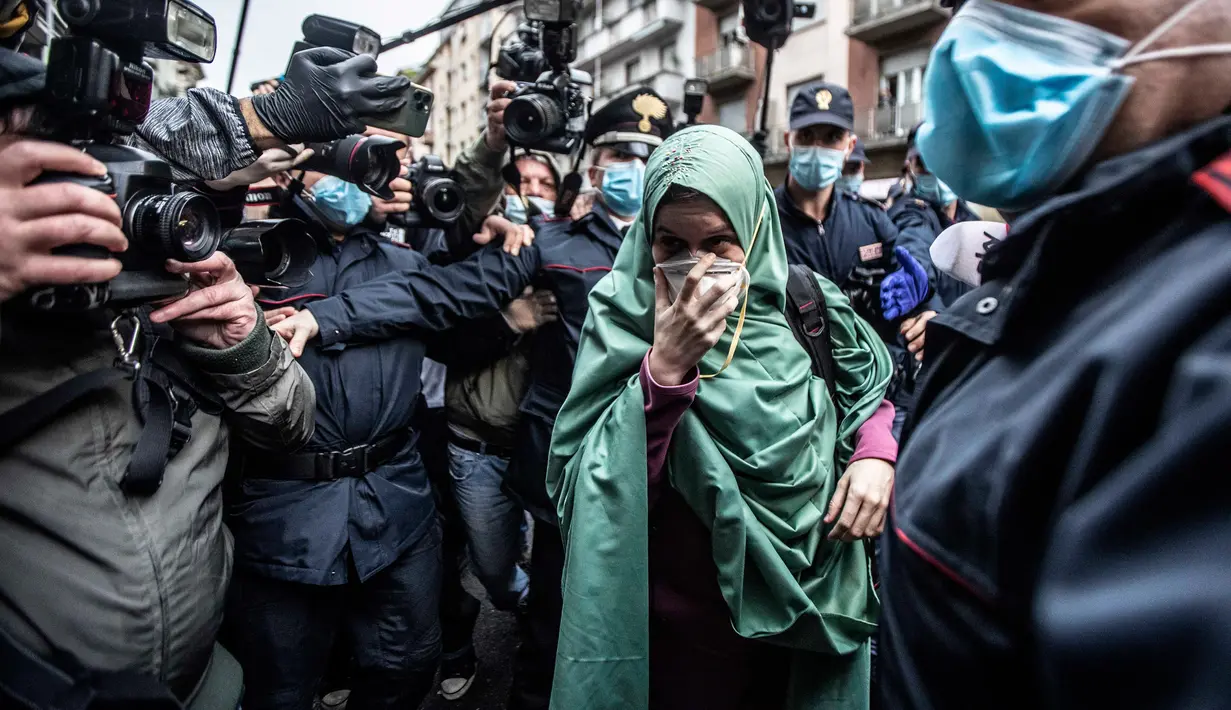 Petugas bantuan Italia bernama Silvia Romano yang dibebaskan oleh militan Somalia, dikawal polisi Italia (Carabinieri), tiba di rumahnya di Milan, 11 Mei 2020. Silvia, 25 tahun, mengakui alasan dia memeluk Islam bukan karena pernikahan atau menjalin hubungan dengan pria mana pun. (AP/Luca Bruno)