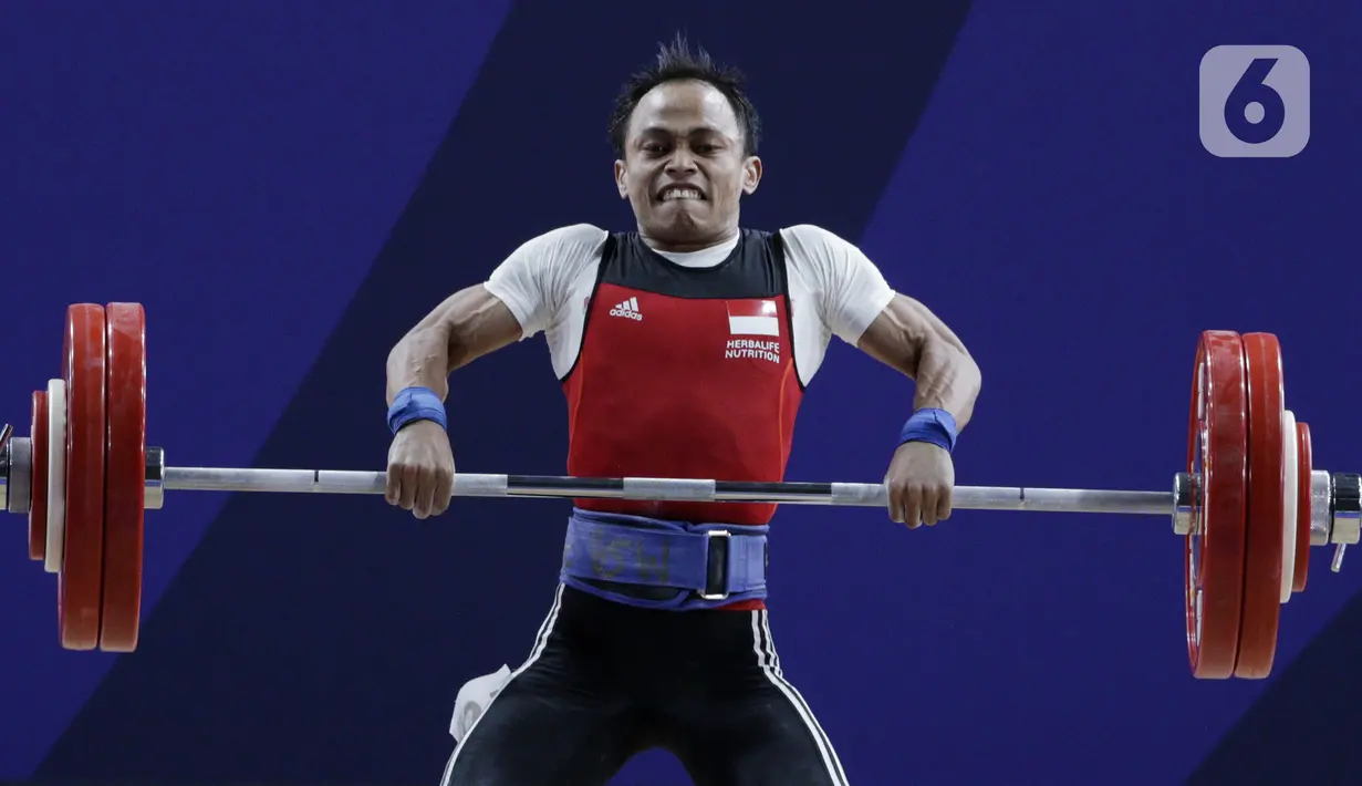 Lifter putra Indonesia, Suratman melakukan angkatan saat SEA Games 2019 cabang angkat besi nomor 55 kg di Stadion Rizal Memorial, Manila, Minggu (1/12/2019). Dirinya meraih perak dengan total angkatan 250 kg. (Bola.com/M Iqbal Ichsan)