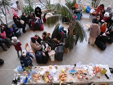 Relawan menyajikan makanan dan minuman untuk pengungsi Ukraina di pusat pengungsi sementara di sekolah dasar setempat di Tiszabecs, Hungaria timur, 28 Februari 2022. Warga Hungaria bergegas ke perbatasan Ukraina untuk membantu pengungsi yang melarikan diri dari invasi Rusia. (Attila KISBENEDEK/AFP)