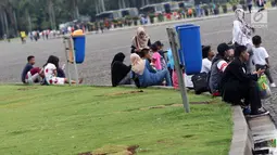 Warga duduk beristirahat di kawasan Monumen Nasional, Jakarta, Jumat (19/4). Libur panjang perayaan Paskah 2019 dimanfaatkan warga untuk berwisata di kawasan Monumen Nasional. (Liputan6.com/Helmi Fithriansyah)