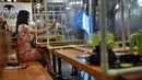 Sepasang pengunjung makan di sela-sela pembatas plastik untuk mencegah penyebaran virus corona di restoran Penguin Eat Shabu di Bangkok, 5 Mei 2020. Restoran kembali dibuka setelah Thailand memperlonggar lockdown dengan mengizinkan tempat makan menerapkan social distancing. (Lillian SUWANRUMPHA/AFP)