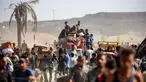 Orang-orang berjalan membawa paket bantuan kemanusiaan yang mereka terima dari pusat distribusi yang dikelola oleh Yayasan Kemanusiaan Gaza (GHF) yang didukung Amerika Serikat (AS) dan Israel, di koridor Netzarim, Nuseirat, Jalur Gaza tengah, pada 30 September 2025. (Eyad BABA/AFP)