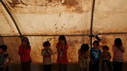 Anak-anak menutupi wajah mereka dalam kegiatan rekreasi di kamp pengungsian al-Bab, Suriah, Selasa (29/5). Anak-anak ini mengikuti berbagai kegiatan, termasuk sekolah darurat, yang digelar oleh para relawan. (AP Photo/Lefteris Pitarakis)