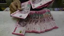 Rupiah ambruk hingga menembus level psikologis di Rp17.500 per dolar AS. Tampak dalam foto, seorang menghitung uang kertas Rupiah di salah satu kantor penukaran uang, Jakarta, Selasa 12 Mei 2026, di tengah depresiasi Rupiah terhadap Dolar Amerika Serikat. (BAY ISMOYO/AFP)