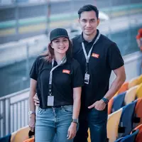 Pasangan selebritis Donna Agnesia dan Darius Sinathrya tengah menyaksikan secara langsung MotoGP di Mandalika. Keduanya tampil kompak kenakan polo shirt warna hitam dan baseball hat. (Instagram/dagnesia).