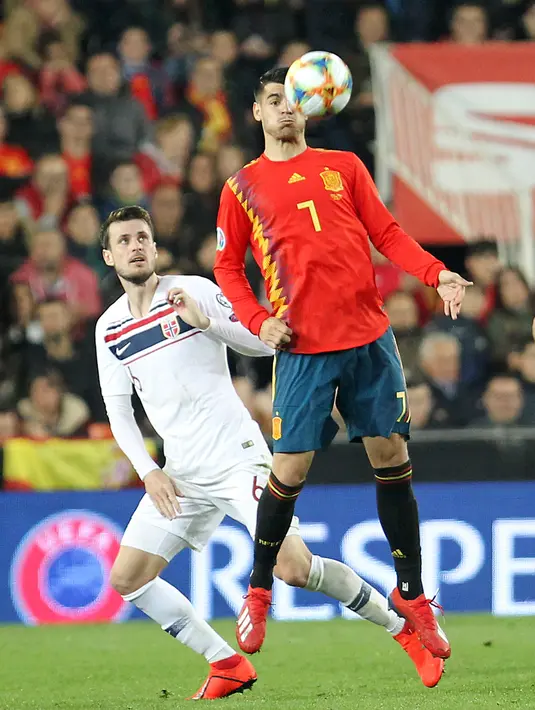 Penyerang Spanyol, Alvaro Morata (depan) berusaha mengontrol bola dari kawalan pemain Norwegia,  Havard Nordtveit selama pertandingan grup F babak kualifikasi Euro 2020 di stadion Mestalla, Valencia (23/3). Spanyol menang tipis atas Norwegia 2-1. (AP Photo/Alberto Saiz)