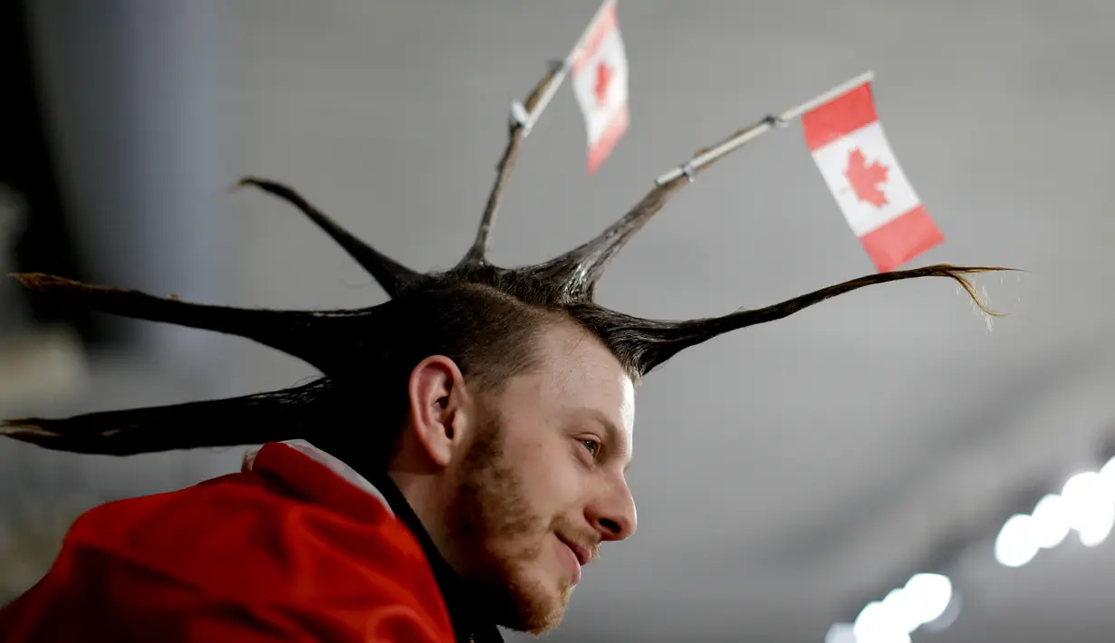 Seorang pria menata rambutnya dengan unik saat menyaksikan cabang curling antara Rusia dan Swiss pada Olimpiade Musim Dingin 2018 di Gangneung, Korea Selatan, Senin (12/2). Ada 92 negara peserta yang mengikuti ajang tersebut. (AP/Natacha Pisarenko)