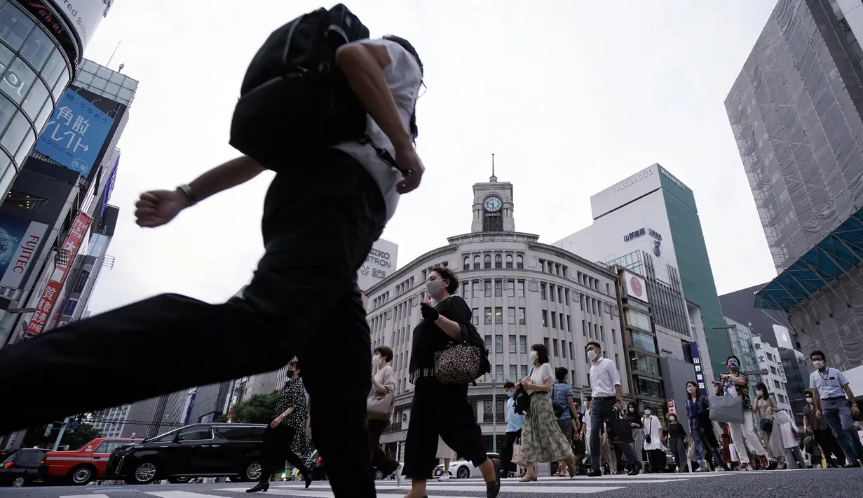 Orang-orang mengenakan masker mencegah penyebaran coronavirus baru berjalan di atas penyeberangan pejalan kaki di Tokyo, Senin, (20/7/2020). Ibukota Jepang hari Senin mengkonfirmasi lebih dari 160 kasus virus corona baru. (AP Photo/Eugene Hoshiko)