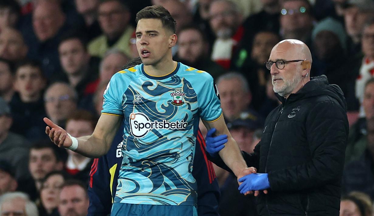 Anggota tim medis Southampton, dr Steve Baynes berusaha mencegah Jad Bednarek memasuki lapangan setelah insiden terjatuh usai duel udara dengan gelandang Arsenal, Gabriel Martinelli pada laga Liga Inggris 2022/2023 di Emirates Stadium, London (21/4/2023). (AFP/Adrian Dennis)