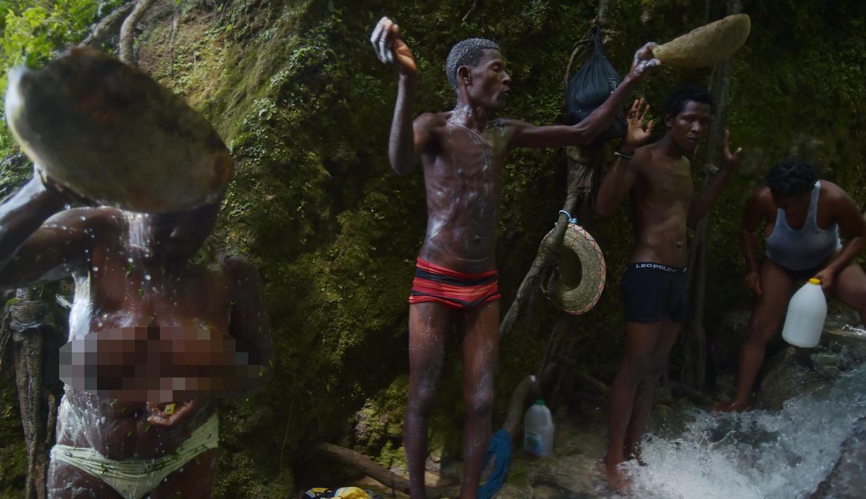 Sejumlah peziarah mandi di bawah air terjun di Saut d' Eau, Haiti (15/7). Bunda Maria tersebut juga dihormati dalam budaya Voodoo dan dipercaya sebagai Dewi Cinta atau Ezili Danto. (AFP Photo/Hektor Retamal)