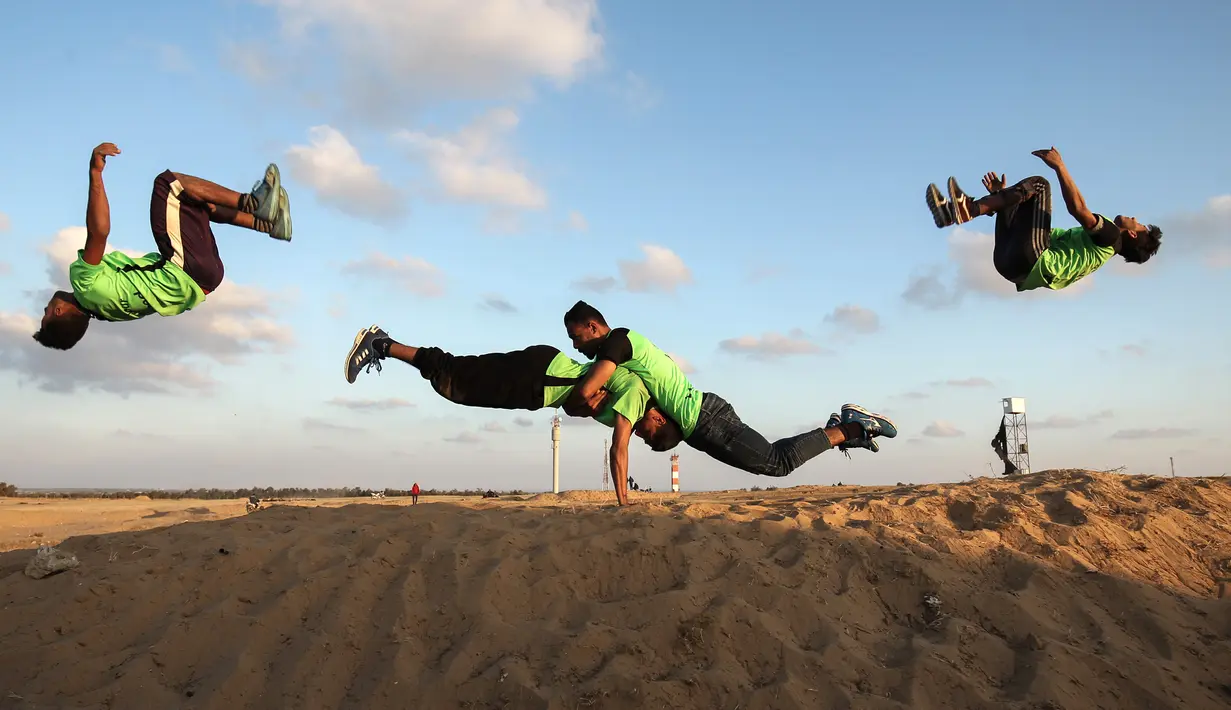 Empat pemuda Palestina melakukan aksi keterampilan parkour di dekat tenda warga di perbatasan Gaza, Palestina (10/4). Sebelumnya sejumlah warga membangun tenda di perbatasan Gaza untuk meminta hak tanah mereka atas Isreal. (AFP Photo/Said Khatib)