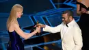 Aktris Nicole Kidman (kiri) memberikan piala kepada Jordan Peele sebagai pemenang kategori original screenplay dalam acara Piala Oscar 2018 di Dolby Theatre di Los Angeles, Amerika Serikat, Minggu (4/3). (Chris Pizzello/Invision/AP)