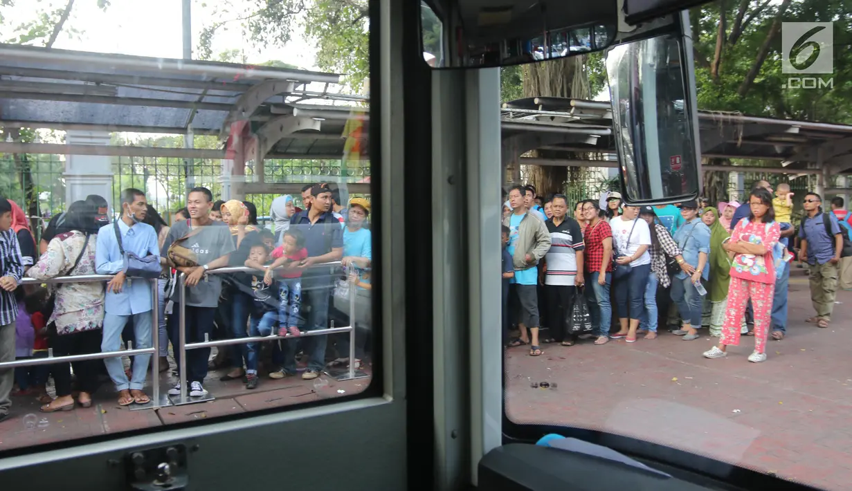 Warga antre untuk menaiki bus tingkat wisata keliling Ibu Kota di kawasan Monas, Jakarta, Sabtu (16/6). Libur Hari Raya Idul Fitri dimanfaatkan oleh sebagian masyarakat Jakarta untuk berlibur ketempat wisata bersama keluarga. (Liputan6.com/Arya Manggala)