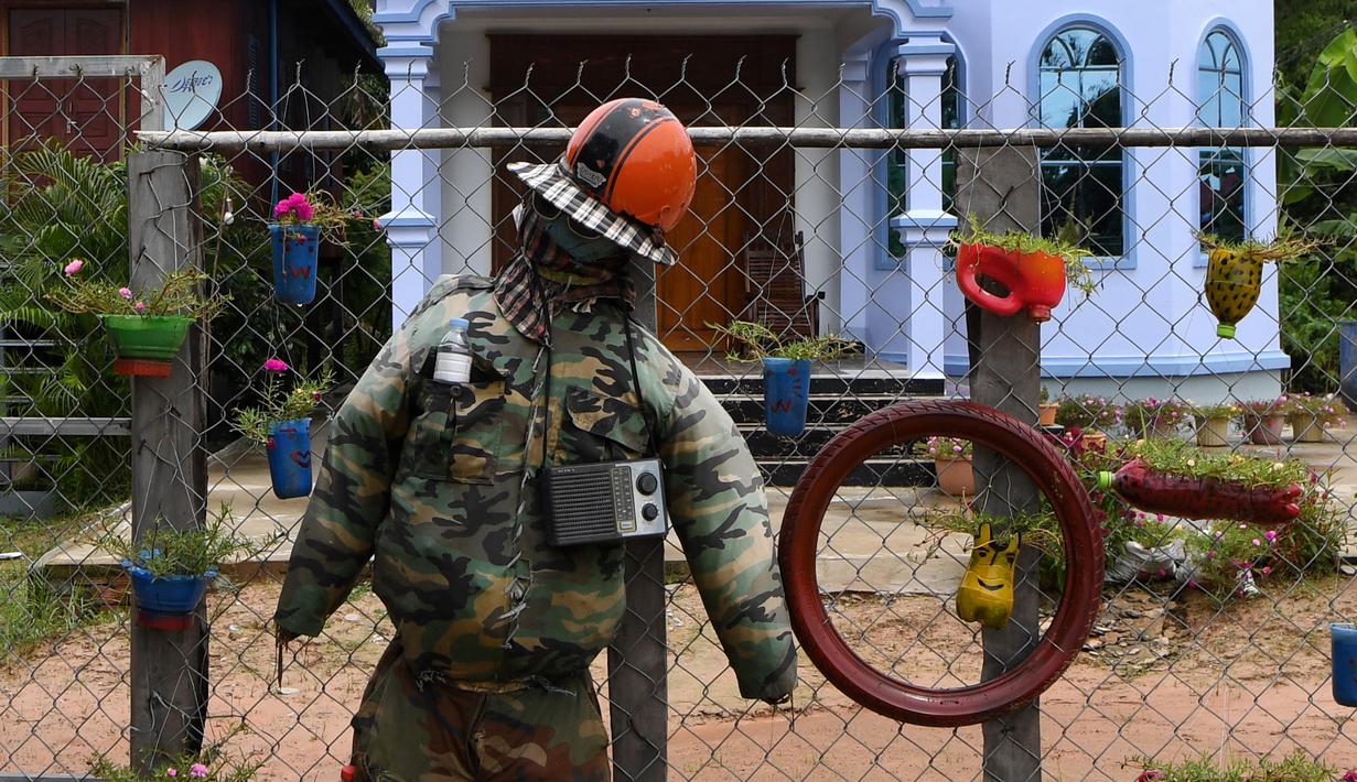Orang-orangan sawah diikat ke pagar di depan sebuah rumah di provinsi Kampong Cham, Kamboja, 11 Oktober 2020. Para petani di desa itu menggunakan orang-orangan sawah atau disebut juga Tim Mong untuk menangkal virus corona  Covid-19 berdasarkan kepercayaan yang mereka yakini. (TANG CHHIN Sothy/AFP)