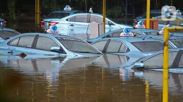 Sejumlah taksi terendam banjir di Pool Taksi Bluebird kawasan Kramat Jati, Jakarta, Selasa (25/2/2020). Meluapnya Kali Cipinang membuat Pool Taksi Blue Bird yang berada tepat di samping kali ikut terdampak banjir. (Liputan6.com/Herman Zakharia)