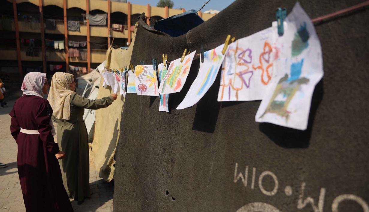 Karya-karya mereka berisi pesan perdamaian, kerinduan akan kehidupan normal, serta seruan untuk menghentikan kekerasan dan genosida di Gaza. Tampak dalam foto, orang-orang melihat pameran yang menampilkan koleksi gambar anak-anak dan perempuan di sebuah sekolah yang diubah menjadi tempat penampungan bagi pengungsi Palestina di kawasan Al-Rimal, Kota Gaza, pada 5 November 2025. (Omar AL-QATTAA/AFP)