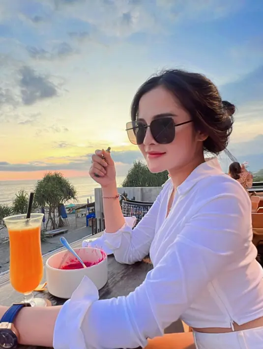 Menikmati senja di pinggir pantai, Bella Bonita memilih gaya simpel dengan kemeja putih. Kemeja putih polos lengan panjang terlihat membentuk tubuhnya dengan sempurna. Foto: Instagram.