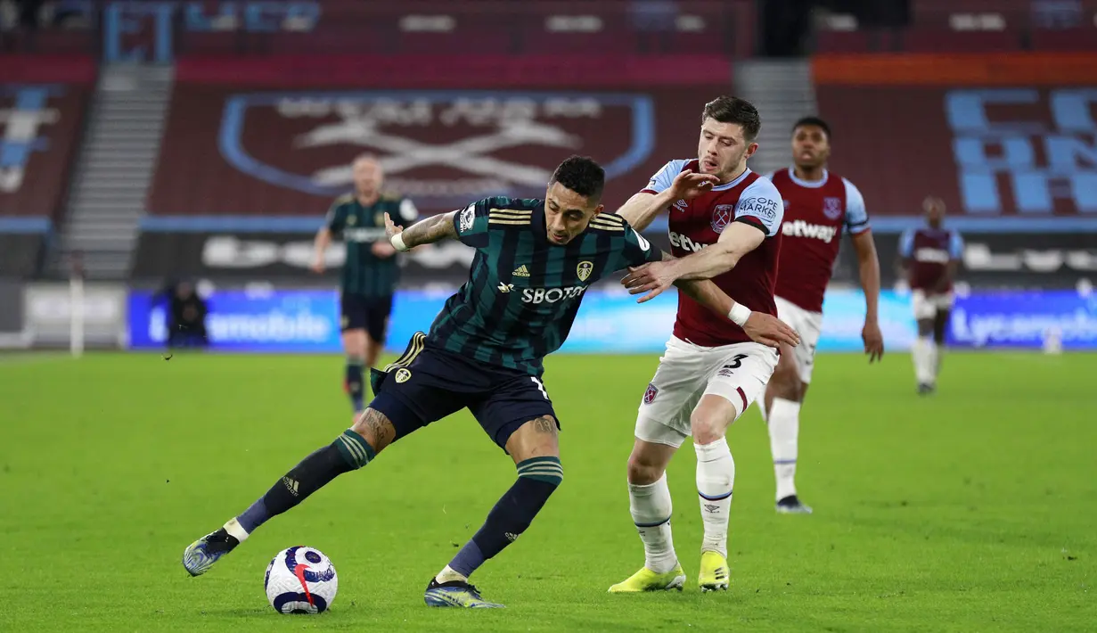 Pemain West Ham United, Aaron Cresswel, berebut bola dengan pemain Leeds United, Raphinha, pada laga Liga Inggris di Stadion London, Senin (8/3/2021). West Ham menang dengan skor 2-0. (Ian Walton, Pool)