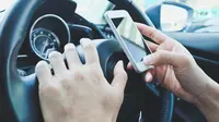 Ilustrasi menyetir sambil main ponsel (iStockPhoto)