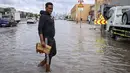 Pengumuman ditegaskan bertujuan menjaga keselamatan warga. Tampak dalam foto, seorang pria menerobos genangan air banjir setelah hujan lebat di Dubai, Uni Emirat Arab (UEA) pada Jumat 19 Desember 2025. (FADEL SENNA/AFP)