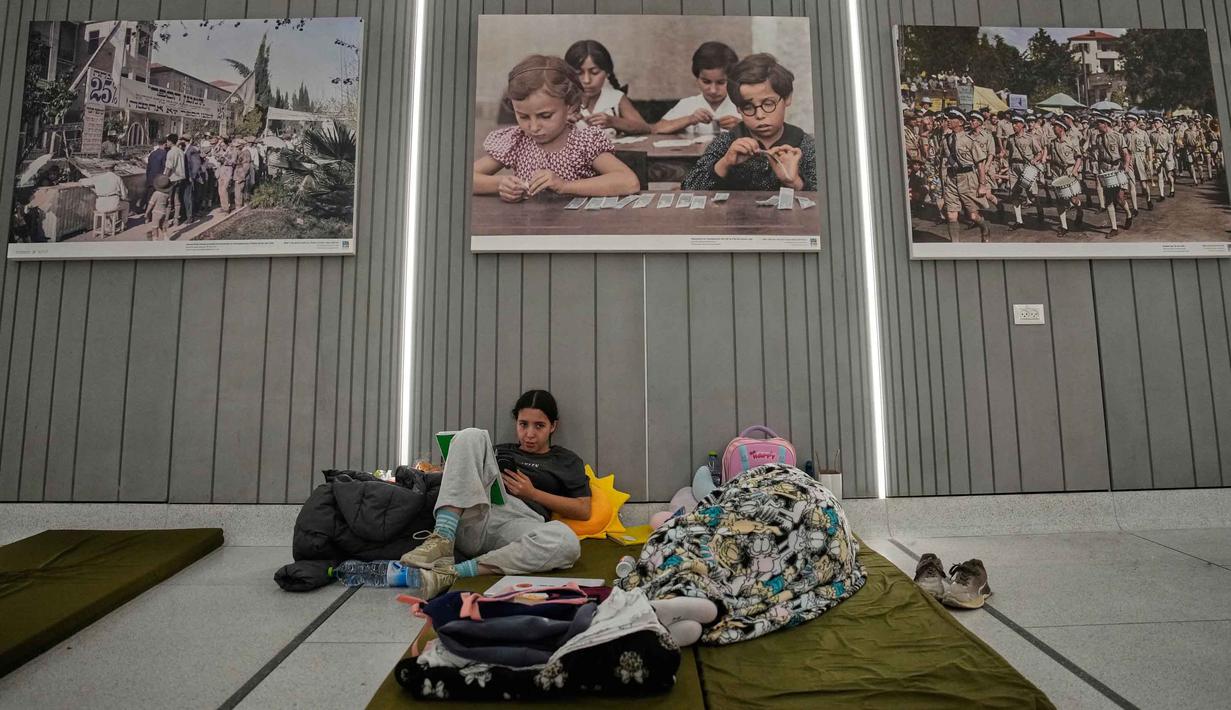 Warga Israel, khususnya di wilayah Tel Aviv dan sekitarnya, saat ini menggunakan stasiun kereta bawah tanah sebagai tempat perlindungan darurat. Tampak dalam foto, orang-orang berlindung di stasiun metro bawah tanah saat sirene serangan udara memperingatkan datangnya rudal Iran di Tel Aviv, Israel, Sabtu, 7 Maret 2026. (AP Photo/Ohad Zwigenberg)