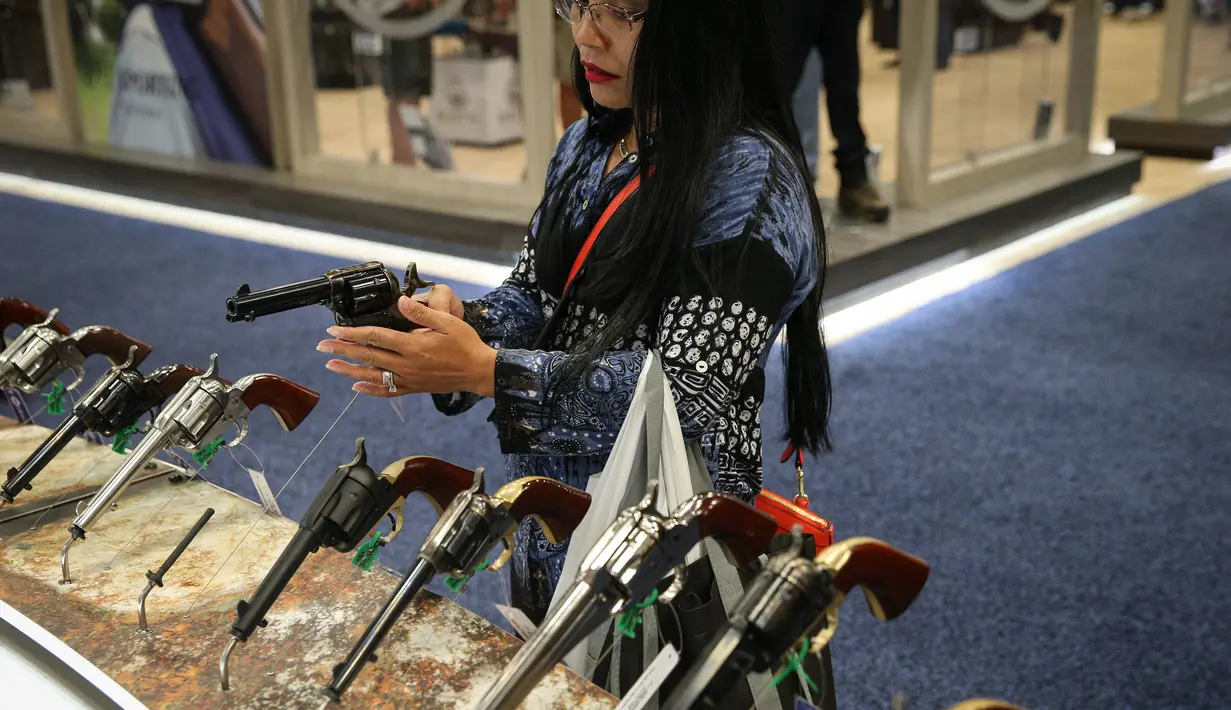 Seorang wanita menjajal pistol di Kay Bailey Hutchison Convention Center saat konvensi tahunan NRA, Texas (6/5). Acara pameran senjata ini dihadiri sekitar 70.000 peserta. (AFP/Loren Elliot)
