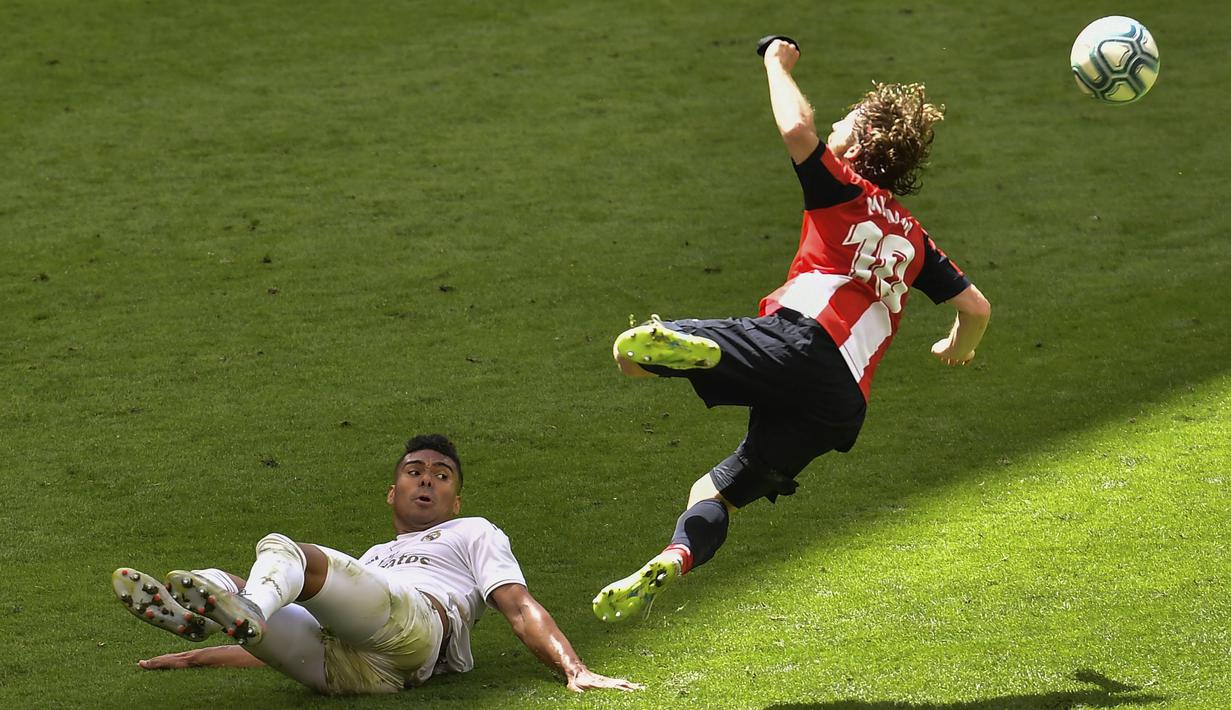 Gelandang Real Madrid, Casemiro, berebut bola dengan pemain Athletic Bilbao, Iker Muniain, pada laga La liga di Stadion San Mames, Minggu (5/7/2020). Real Madrid menang 1-0 atas Athletic Bilbao. (AP/Alvaro Barrientos)