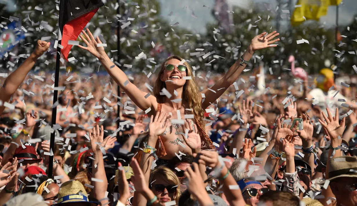 Pengunjung wanita berjoget saat menyaksikan konser selama Festival Glastonbury di Worthy Farm, Somerset, Inggris (30/6/2019). Gelombang panas yang melanada bagian-bagian Eropa tidak menyurutkan pengunjung untuk berkumpul di festival ini. (AP Photo/Joel C Ryan)
