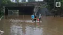 Warga berjalan kaki melintasi kawasan DI Panjaitan, Jakarta, Selasa (25/2/2020). Hujan yang mengguyur Jakarta sejak dini hari tadi membuat kawasan tersebut terendam banjir sehingga tak bisa dilintasi kendaraan bermotor. (Liputan6.com/Herman Zakharia)
