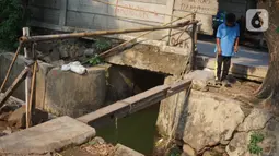 Pejalan kaki melewati tembok berlubang di Terminal Kampung Rambutan, Jakarta, Kamis (19/12/2019). Jauhnya akses bagi pejalan kaki menjadikan tembok berlubang tersebut pintu alternatif untuk keluar dan masuk Terminal Kampung Rambutan. (Liputan6.com/Immanuel Antonius)