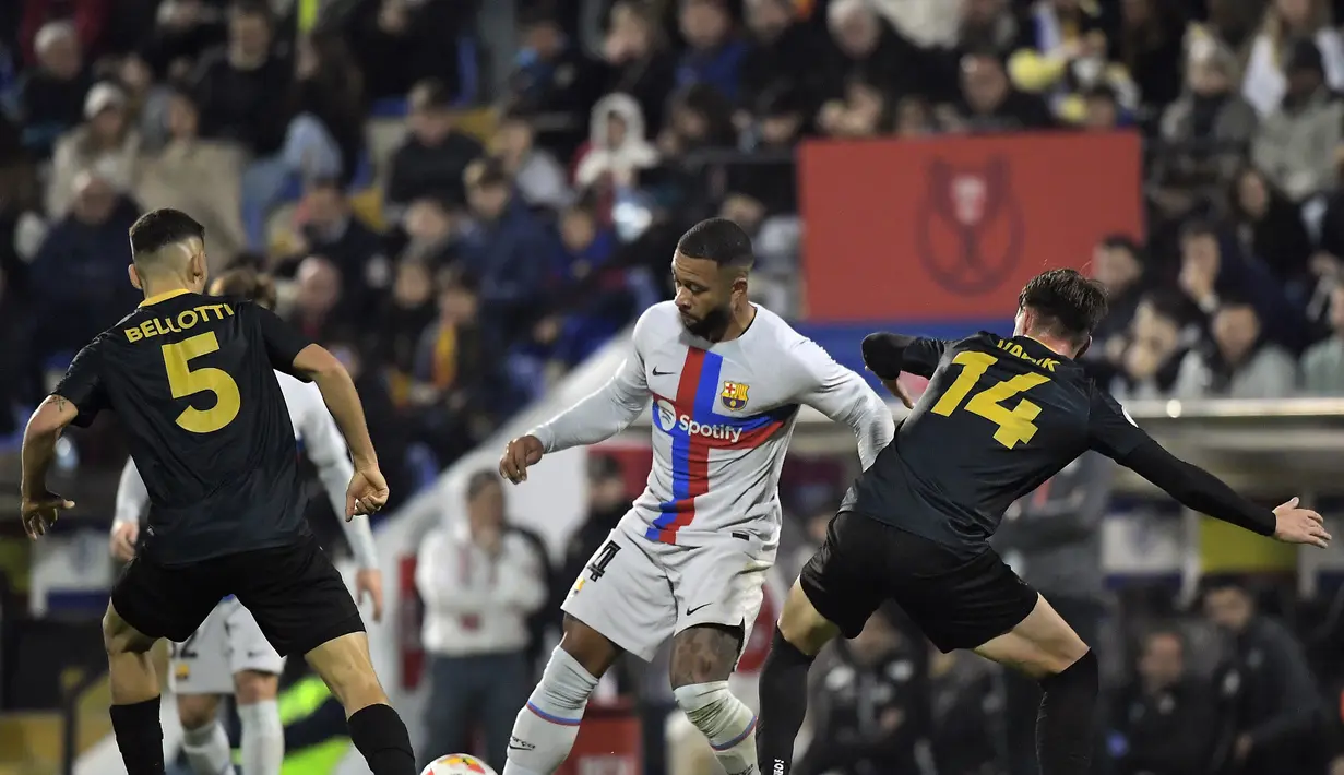 Penyerang Barcelona, Memphis Depay berusaha melewati dua pemain Intercity, Martin Bellotti dan Vadik Murria pada babak 32 besar Copa del Rey di stadion Ricardo Perez di Alicante, Spanyol, Kamis (5/1/2023). Barcelona menang atas Intercity dengan skor tipis 4-3. (AFP/Jose Jordan)