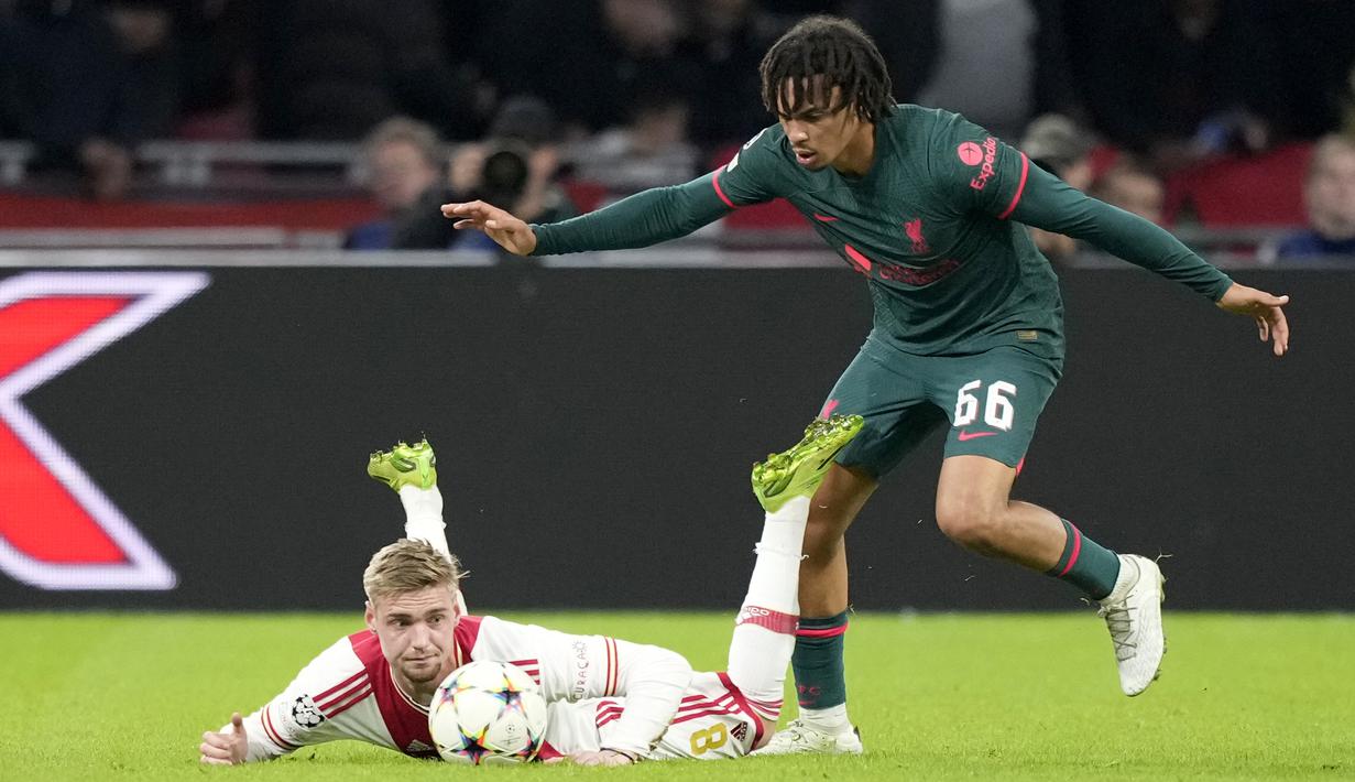 Gelandang Ajax Amsterdam Kenneth Taylor jatuh ke tanah di sebelah bek Liverpool Trent Alexander-Arnold pada matchday kelima Grup A Liga Champions 2022-2023 di Johan Cruiff Arena,  Kamis (27/10/2022) dini hari WIB. The Reds melaju usai menang telak 3-0 di kandang Ajax Amsterdam. (AP Photo/Peter Dejong)