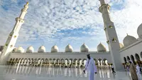 Seorang pria berjalan melewati halaman Masjid Agung Sheikh Zayed di Abu Dhabi, Uni Emirat Arab. Masjid ini adalah masjid terbesar ketiga di dunia setelah masjid di Mekkah dan Madinnah. (Photo by Vincenzo PINTO / AFP)