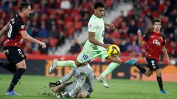 Pemain Barcelona, Lamine Yamal berusaha melewati kiper Mallorca, Leo Roman pada laga lanjutan Liga Spanyol 2024/2025 di Stadion Mallorca Son Moix, Mallorca, Spanyol, Rabu (04/12/2024) dini hari WIB. (AFP/Jaime Reina)