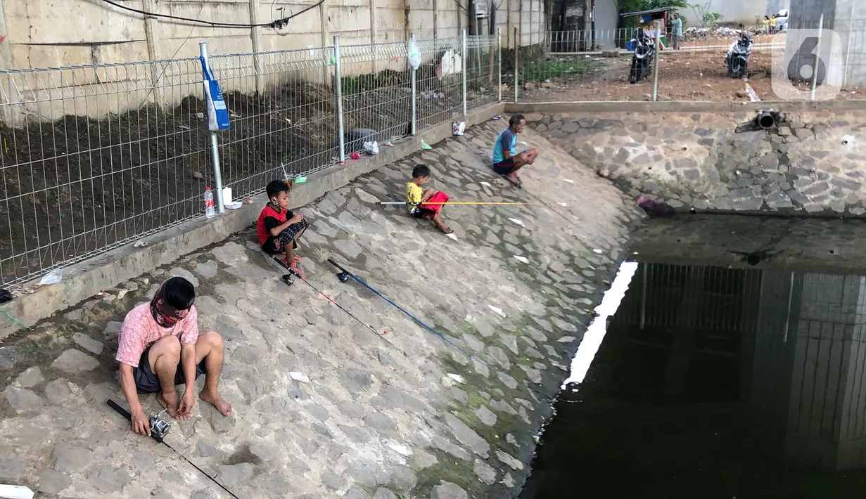 Sejumlah warga memancing ikan di kubangan yang berada di Jalan DI Panjaitan, Jatinegara, Jakarta, Selasa (16/6/2020). Meski telah dipagari, sejumlah warga tetap memancing ikan di lokasi yang merupakan saluran pembuangan tersebut. (Liputan6.com/Immanuel Antonius)