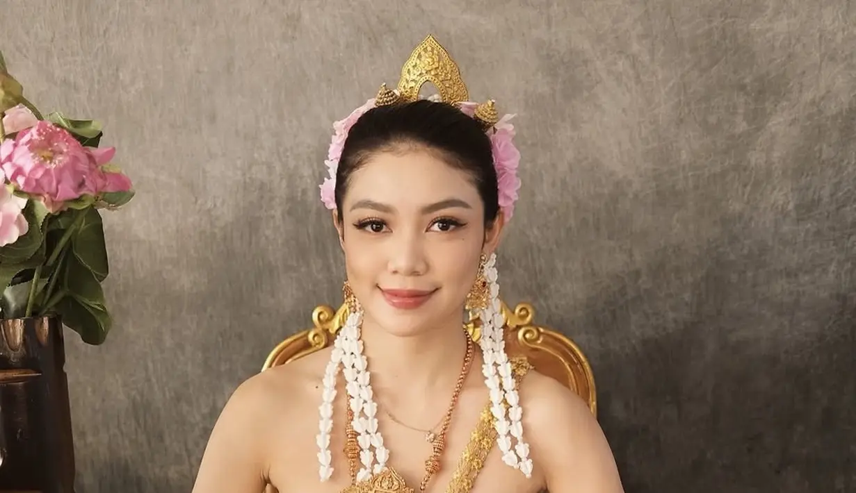 Dalam foto yang diunggah, Regina Phoenix menunjukkan pesona luar biasa dengan baju adat Thailand, Chut Thai, yang memperlihatkan keindahan budaya tradisional negeri gajah putih. Suasana yang elegan dan berkelas terlihat saat Regina duduk di kursi berlapis emas dengan latar belakang yang klasik. Senyum lembutnya menambah daya tarik, membuat setiap orang yang melihatnya terpesona. (Liputan6.com/IG/@reginaaphx)