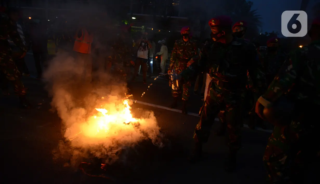 Anggota Marinir memadamkan api dari sisa pendemo yang menolak Omnibus Law UU Cipta Kerja di kawasan Patung Kuda, Jakarta, Selasa (20/10/2020).  Anggota Marinir membubarkan dan mengawal pulang massa pendemo  ke rumah masing-masing. (merdeka.com/Imam Buhori)