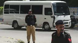 Petugas polisi berjaga-jaga saat pemain kriket Inggris dan ofisial tim melakukan perjalanan dengan bus saat tiba di hotel mereka di Karachi pada 15 September 2022. Tim kriket Inggris tiba di Pakistan setelah 17 tahun, untuk memainkan tujuh pertandingan kriket Twenty20, mulai dari 20 September. (AFP Photo/Rizwan Tabassum)