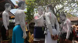 Para pemuda melukis diri mereka untuk persiapan ritual Hindu yang disebut "Grebeg" di Desa Tegallalang, Bali, Rabu (30/1). Tradisi ritual berkeliling kampung dengan riasan tubuh warna-warni itu dipercaya sebagai penangkal Roh jahat. (AP/Firdia Lisnawati)