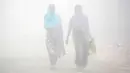 Warga berjalan melalui kabut tebal akibat polusi di Delhi, India (1/12). Sekitar 26 penerbangan ditunda atau dialihkan di Delhi sementara tiga dibatalkan, menurut situs IGI. (REUTERS/Cathal McNaughton)