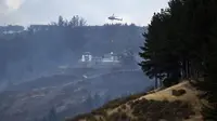 Sebuah helikopter dikerahkan ke lokasi kebakaran hutan yang melanda distrik Port Hills, kota Christchurch di Selandia Baru, Kamis (16/2). Sedikitnya 17 helikopter dan pesawat telah dikerahkan untuk membantu proses pemadaman api. (OLIVER WATSON/AFP)