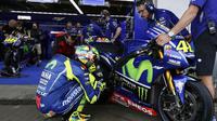 Pebalap Movistar Yamaha, Valentino Rossi, berjongkok di sisi motor YZR-M1 miliknya pada sesi latihan bebas pertama MotoGP Spanyol di Sirkuit Jerez, 5 Mei 2017. (EPA/Jose Manuel Vidal)