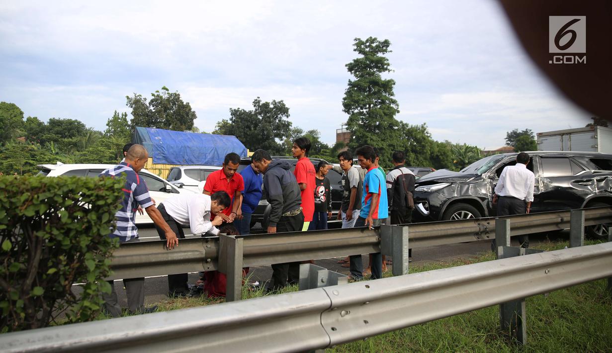Pengendara membantu korban kecelakaan antara mobil Toyota Fortuner dengan truk boks Colt Diesel di tol Jagorawi, Kamis (28/12). Kecelakaan membuat Fortuner hitam itu rusak parah di bagian kiri. (Liputan6.com/Angga Yuniar)