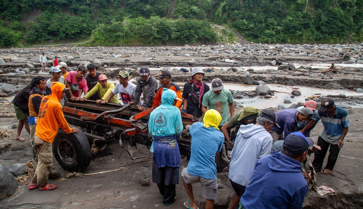 Tiga truk dilaporkan terseret aliran sungai, sementara 12 truk lainnya terjebak di area yang dipenuhi material. Tampak dalam foto, warga berusaha mengevakuasi truk yang rusak dan terkubur di pasir setelah longsor lumpur akibat hujan dari Gunung Merapi di Sungai Senowo, Magelang, Jawa Tengah pada Rabu 4 Maret 2026. (Devi Rahman/AFP)