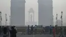 Pejalan kaki berjalan di sepanjang jalan dekat Gerbang India di tengah kabut asap tebal di New Delhi, Kamis (3/11/2022). Setiap musim dingin, udara dingin beserta asap dari petani yang membakar jerami dan emisi kendaraan juga sumber-sumber lainnya bercampur menciptakan kabut asap mematikan. (Money SHARMA / AFP)
