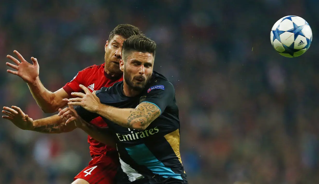  Pemain Bayern Munich Xabi Alonso berebut bola dengan pemain Arsenal Olivier Giroud pada lanjutan Liga Champion di Allianz Arena, Munich, Jerman, Kamis (5/11/15) dini hari. Bayern menang 5-1. (Reuters / Michael Dalder)