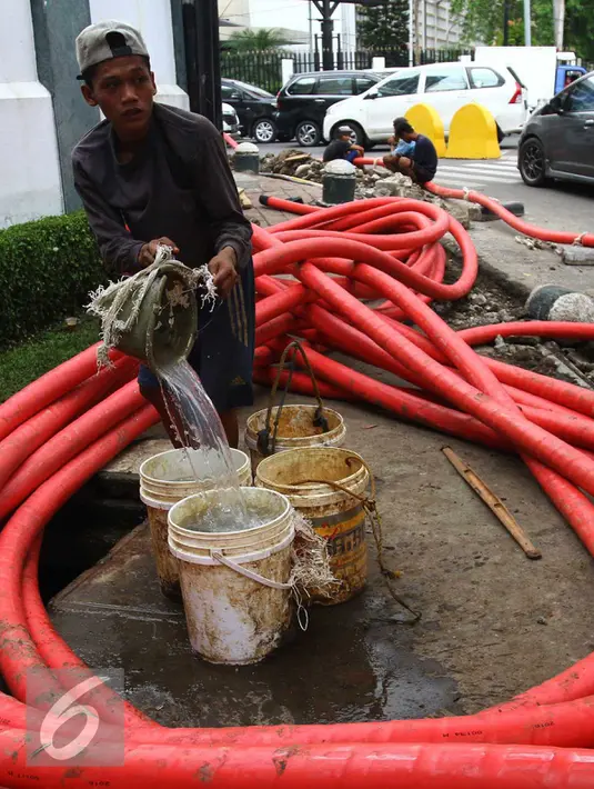 Seorang pekerja menyiapkan air untuk proyek pemasangan instalasi listrik bawah tanah di Jakarta, Jumat (28/10). Para buruh lepas ini mengaku mendapat upah sebesar Rp.200.000 per hari. (Liputan6.com/Angga Yuniar)