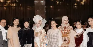 Nagita Slavina tampil mengenakan inner putih lengan panjang dengan kerah circle berkerut. Dipadukan long dress motif kotak-kotak model spaghetti strap. [@drfeninugraha.spgk]