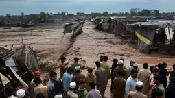 Warga terlihat pasrah melihat bangunan rumahnya hanyut tersapu banjir bandang di kawasan pasar di Peshawar, Pakistan, Minggu (3/4). Bencana yang menerjang wilayah Peshawar telah menghancurkan 852 rumah warga. (AFP/A Majeed)